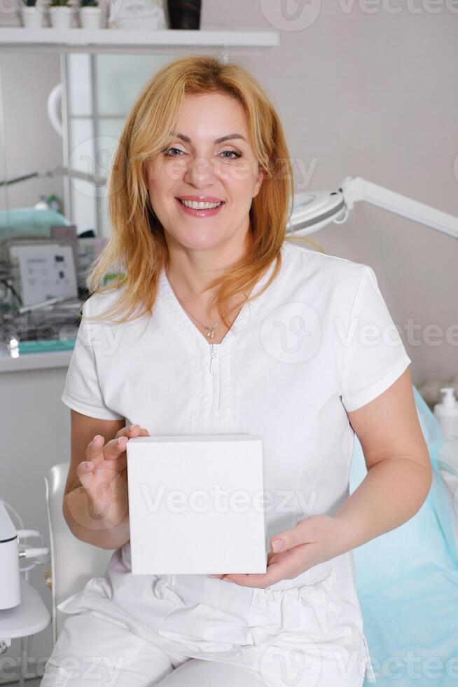 Smiling Cosmetologist Presenting Blank Product Box photo