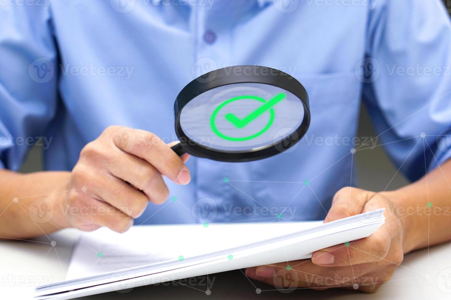 Close up hand of businessperson looking at documents through magnifying glass. Concept of business and data validation. photo