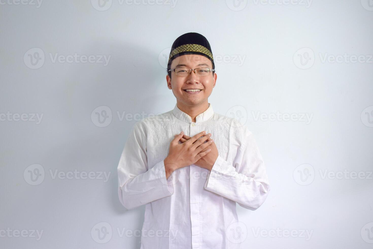 asiático musulmán hombre vistiendo lentes y blanco paño haciendo mano en cofre actitud para ramadhan y eid Alabama fitr. aislado blanco antecedentes foto