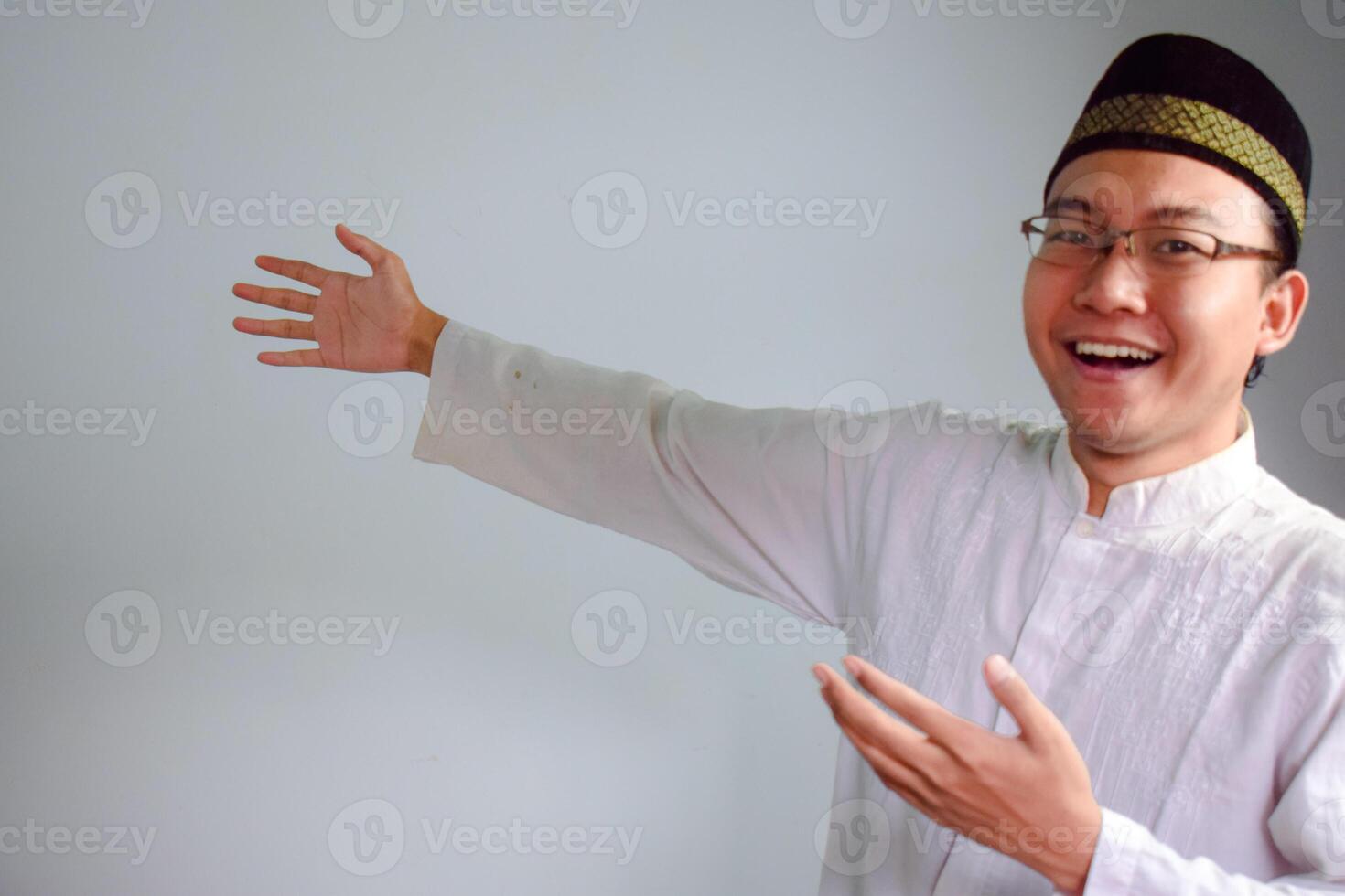 Asian Muslim man wearing glasses and white cloth welcoming pose for ramadhan and eid al fitr. Isolated white background photo