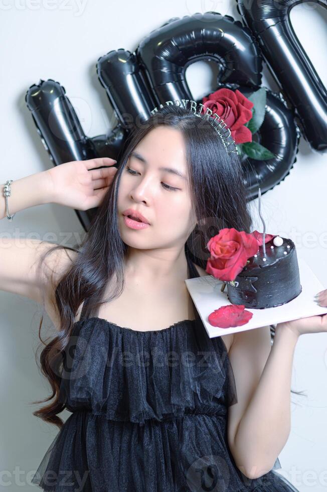 Beautiful woman wearing a black dress and chocolate cake in the concept of birthday photo