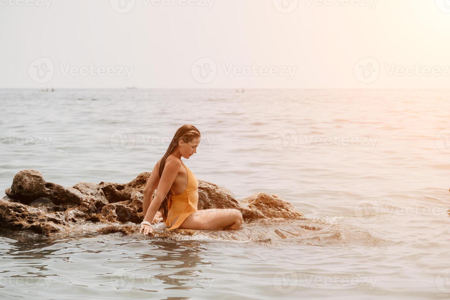 mujer viaje mar. contento turista en sombrero disfrutar tomando imagen al aire libre para recuerdos. mujer viajero posando en el playa a mar rodeado por volcánico montañas, compartiendo viaje aventuras viaje foto