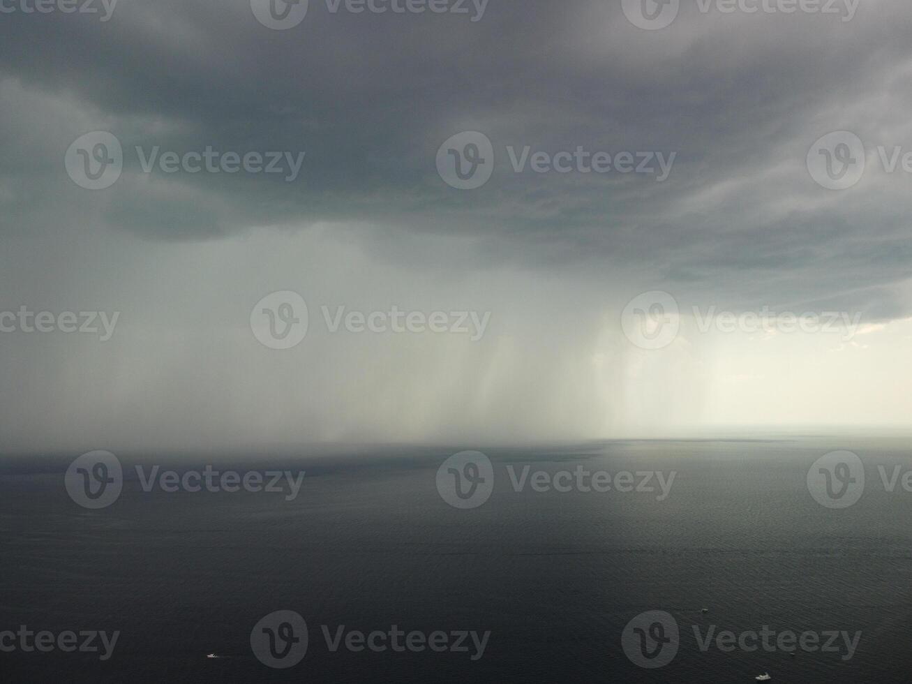 Aerial view footage of rain clouds over sea ocean Black clouds in bad weather day over sea surface High angle view nature view. Apocalypse. Storm Large freight dark gloomy rain clouds over a calm sea. photo