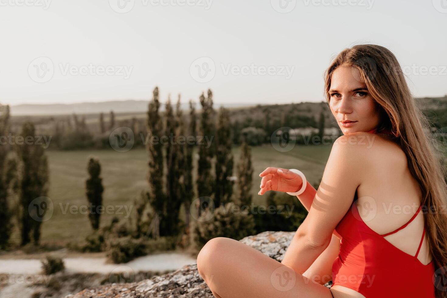 bien mirando medio Envejecido mujer con largo cabello, aptitud instructor en polainas y tapas haciendo extensión y pilates en el rock cerca bosque. hembra aptitud yoga rutina concepto. sano estilo de vida foto