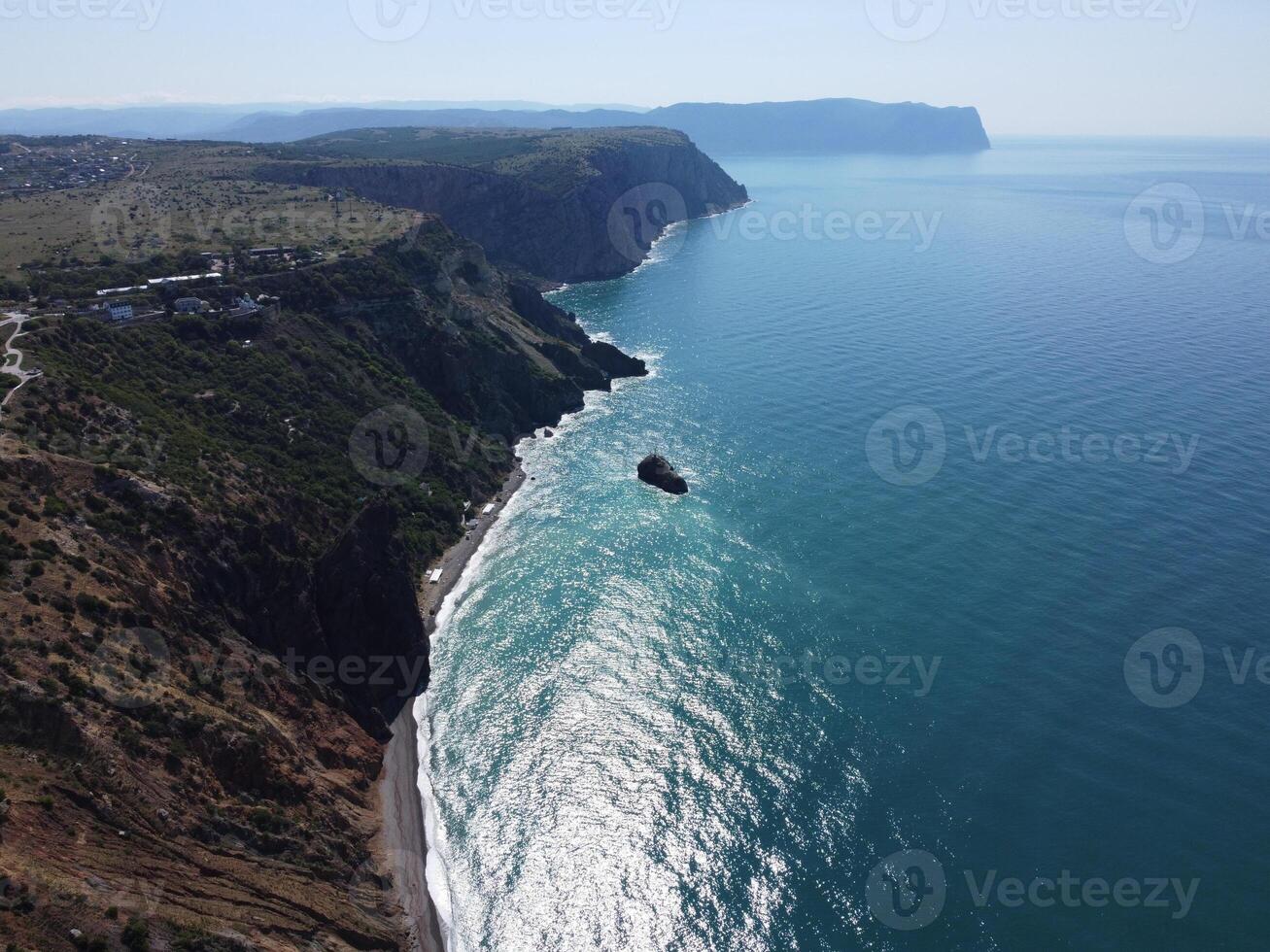 Aerial view from above on calm azure sea and volcanic rocky shores. Small waves on water surface in motion blur. Nature summer ocean sea beach background. Nobody. Holiday, vacation and travel concept photo