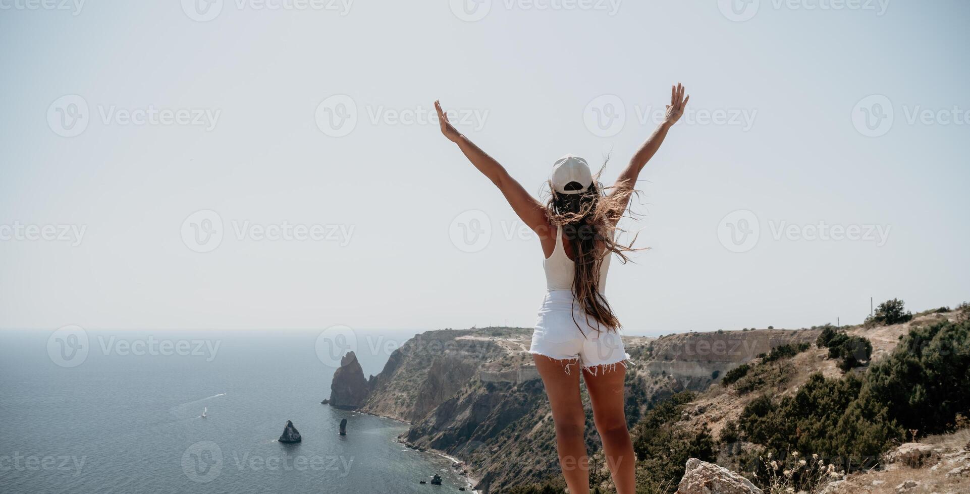 Woman summer travel sea. Happy tourist enjoy taking picture outdoors for memories. Woman traveler posing over sea bay surrounded by volcanic mountains, sharing travel adventure journey photo