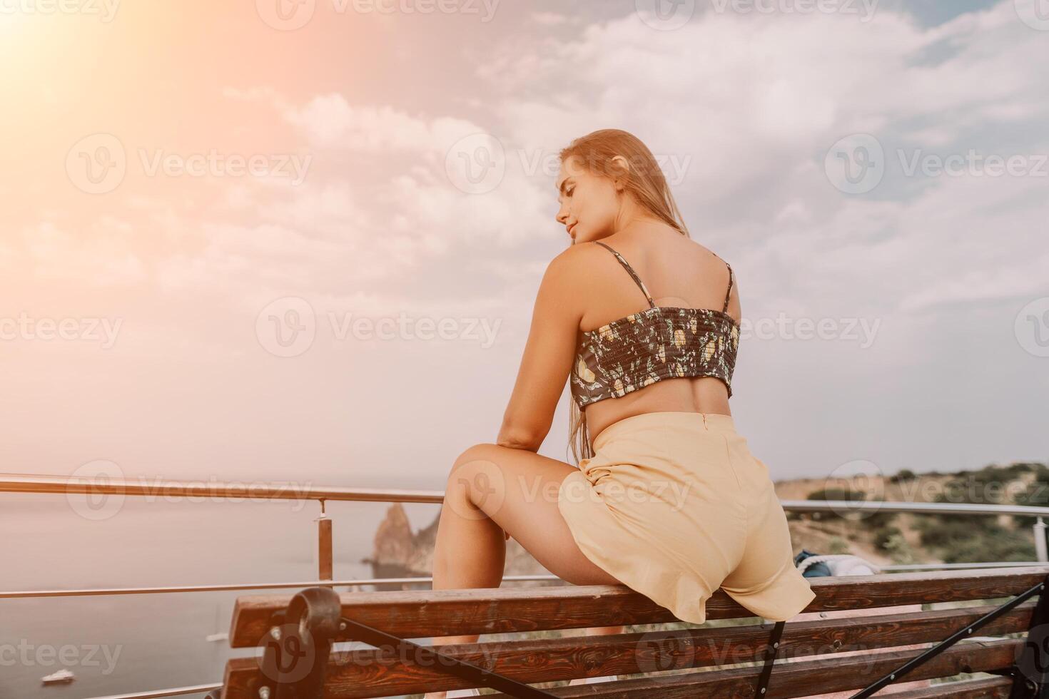 Woman travel sea. Happy tourist enjoy taking picture outdoors for memories. Woman traveler looks at the edge of the cliff on the sea bay of mountains, sharing travel adventure journey photo