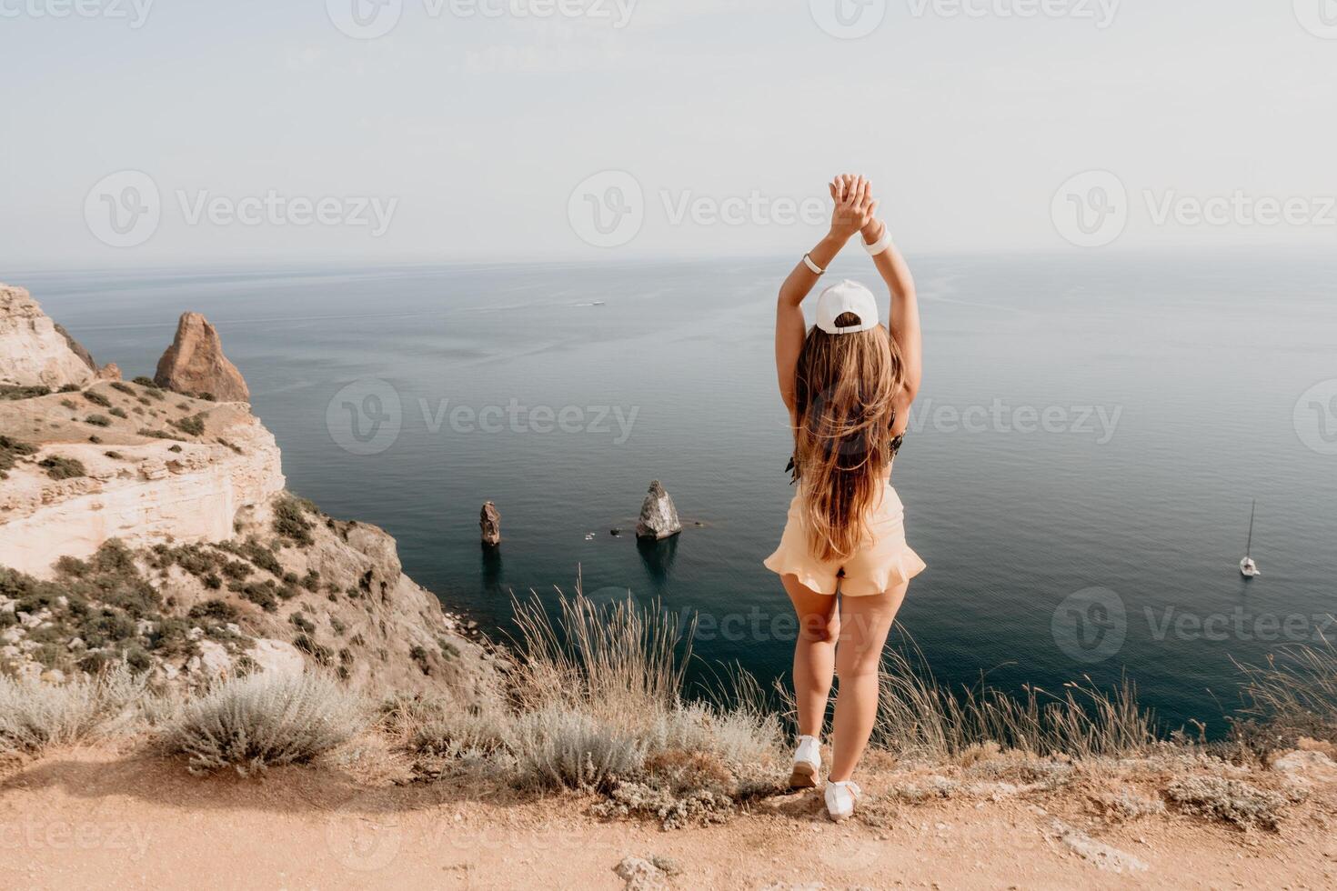 Woman travel sea. Happy tourist taking picture outdoors for memories. Woman traveler looks at the edge of the cliff on the sea bay of mountains, sharing travel adventure journey photo