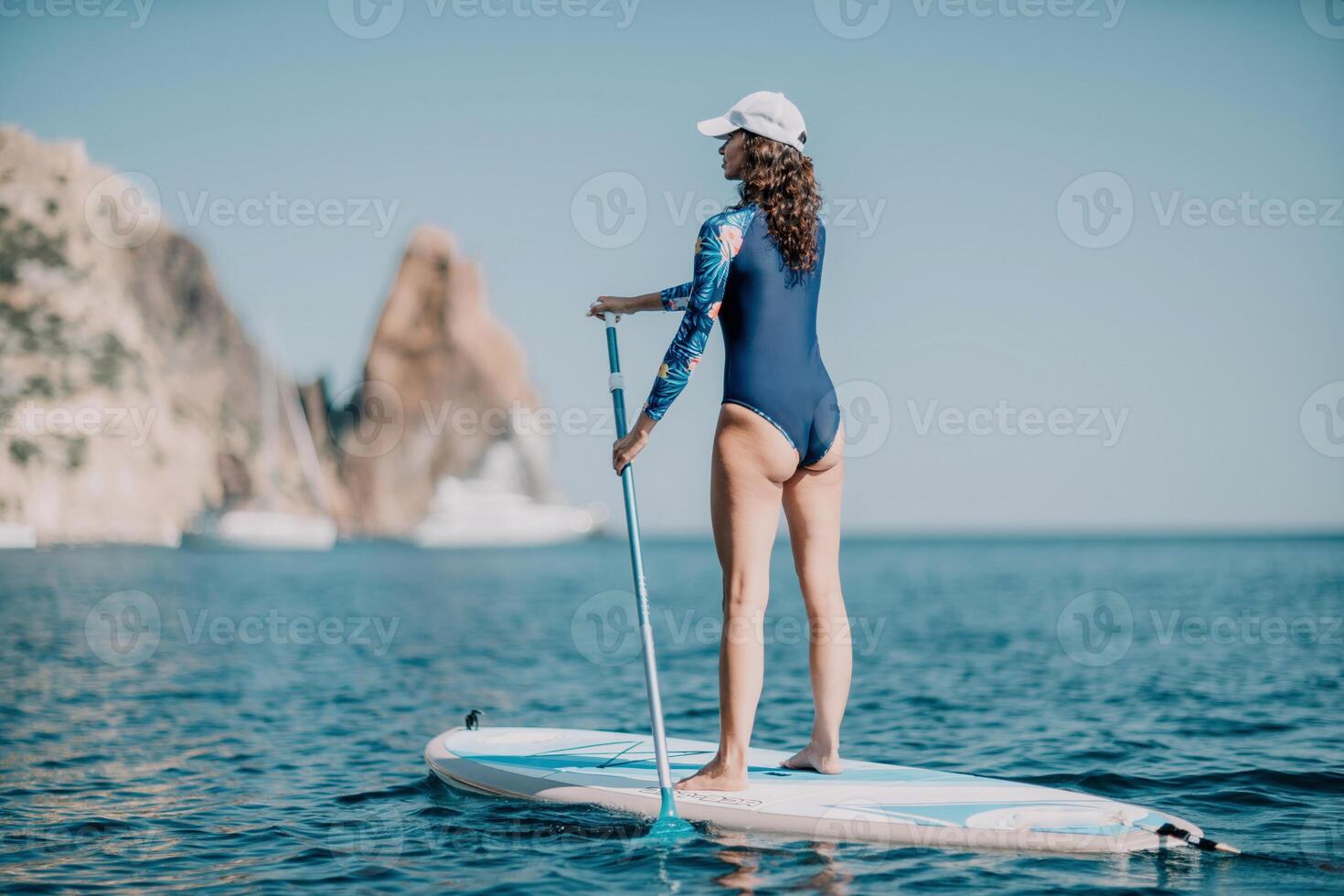 Woman sup yoga. Middle age sporty woman practising yoga pilates on paddle sup surfboard. Female stretching doing workout on sea water. Modern individual female hipster outdoor summer sport activity. photo