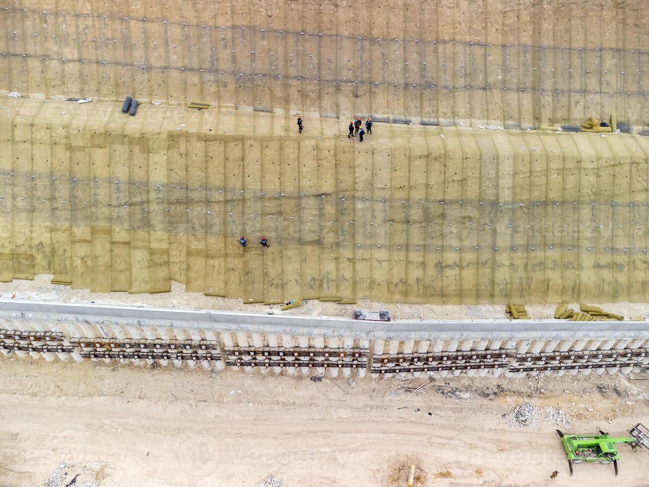 Mountain road constraction. Workers reinforce the slope over the new road. Road construction in progress on slope nature canyon. Infrastructure development and logistics. Aerial drone shot photo