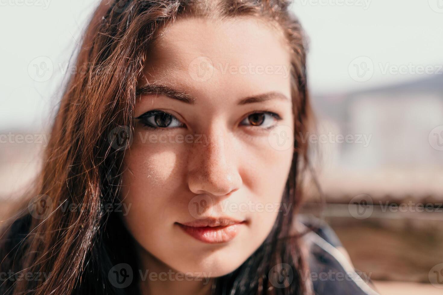 contento joven sonriente mujer con pecas al aire libre retrato. suave soleado colores. al aire libre de cerca retrato de un joven morena mujer y mirando a el cámara, posando en contra otoño naturaleza antecedentes foto