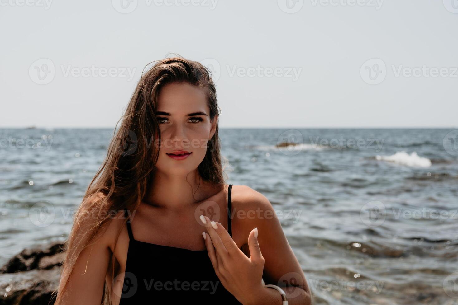 Woman summer travel sea. Happy tourist in hat enjoy taking picture outdoors for memories. Woman traveler posing on the beach at sea surrounded by volcanic mountains, sharing travel adventure journey photo