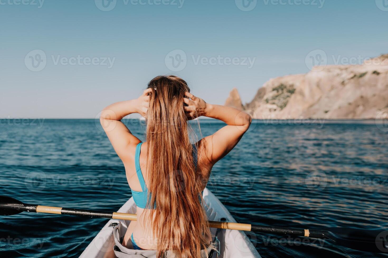 Woman in kayak back view. Happy young woman with long hair floating in kayak on calm sea. Summer holiday vacation and cheerful female people relaxing having fun on the boat. photo