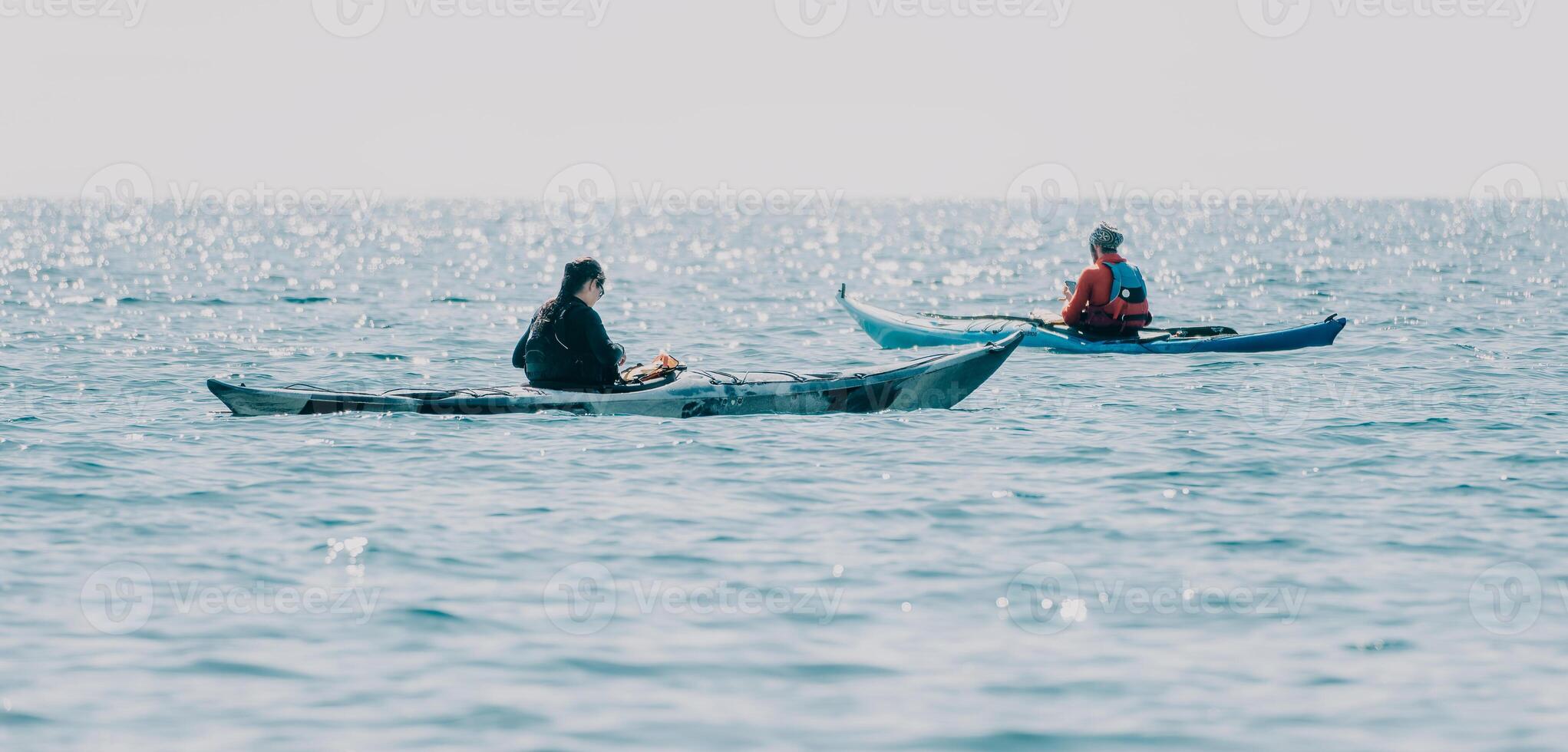 Man woman sea kayak. Happy free man and woman in kayak on ocean, paddling with wooden oar. Calm sea water and horizon in background. Active lifestyle at sea. Summer vacation. photo