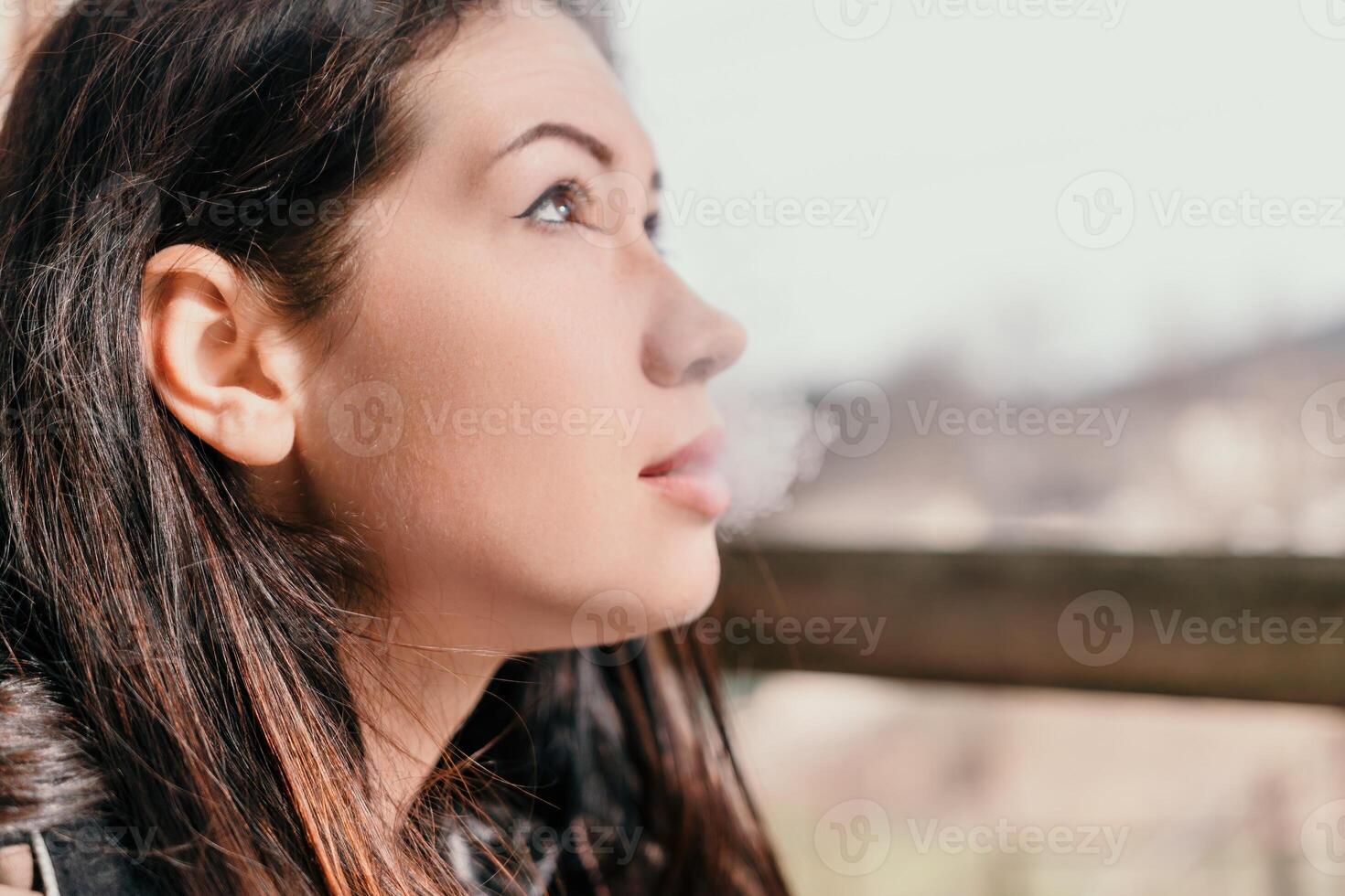 Happy young smiling woman with freckles outdoors portrait. Soft sunny colors. Outdoor close-up portrait of a young brunette woman and looking to the camera, posing against autumn nature background photo