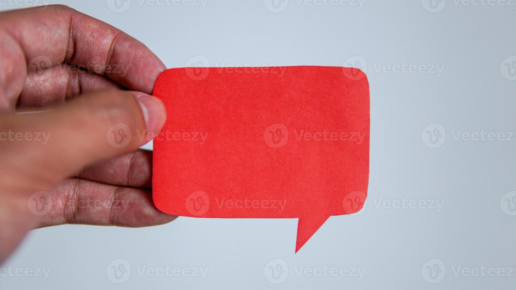 Man's hand holding a red message speech bubble. Man conveying important information with paper speech bubble. photo