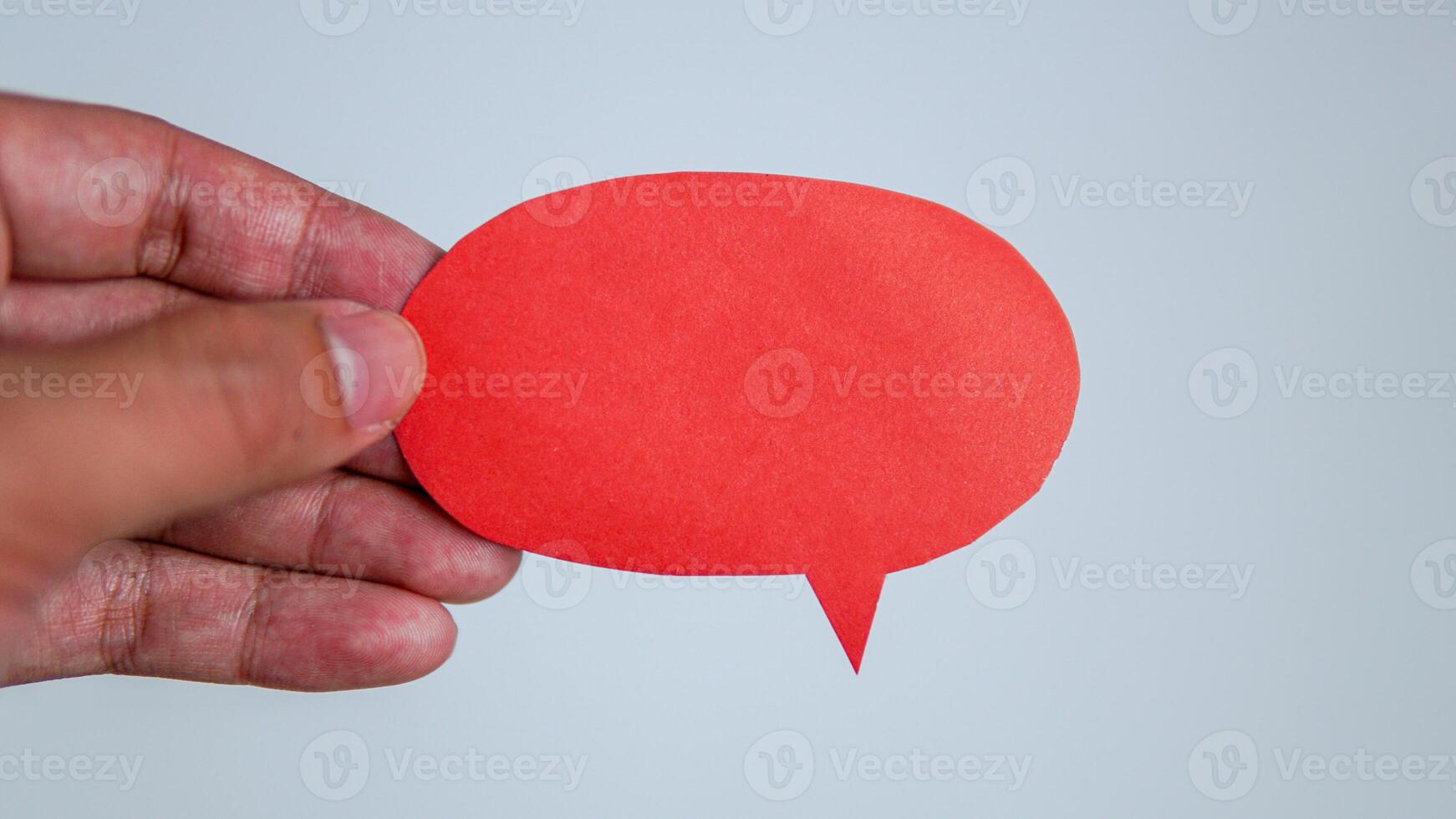 Man's hand holding a red message speech bubble. Man conveying important information with paper speech bubble. photo