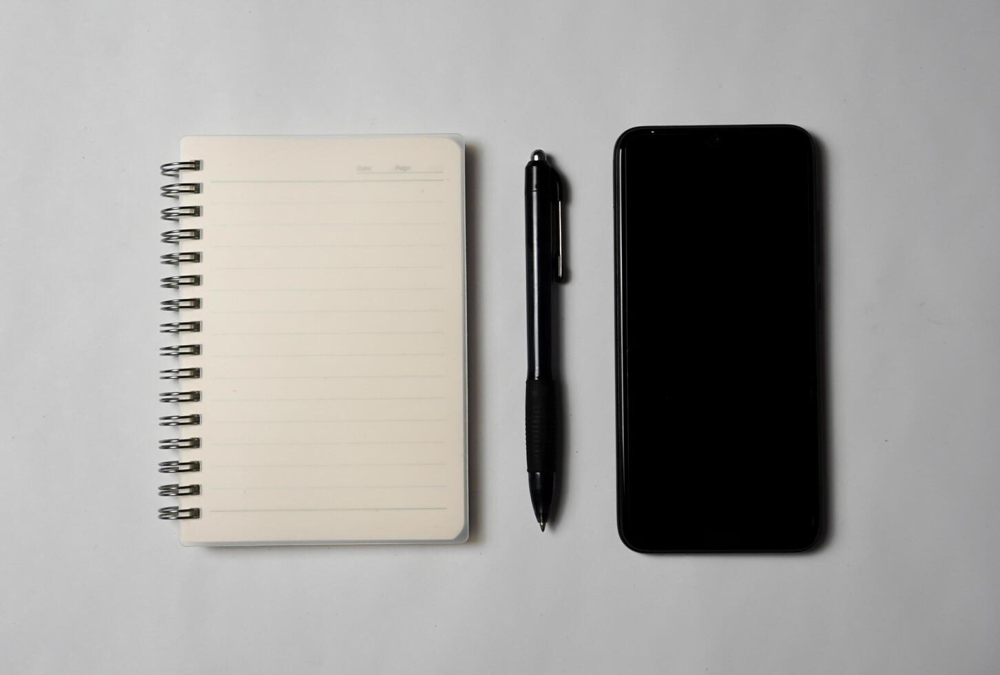Seen from above there is a notebook with a pen and a smartphone. photo
