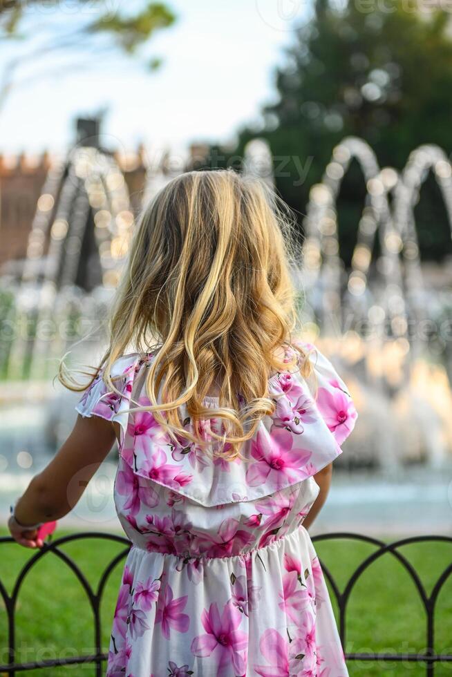 Small girl in beautiful dress admiring fountain in Verona Italy photo