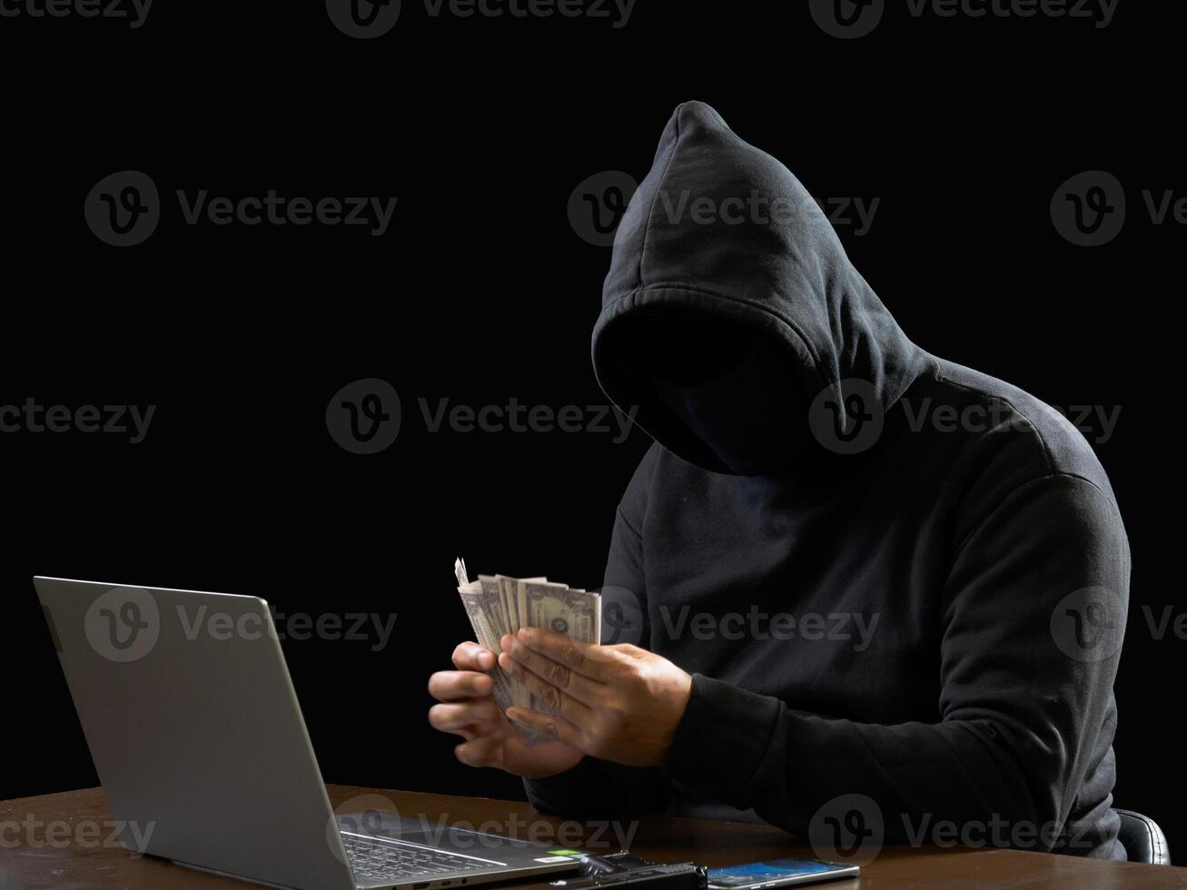 Portrait hacker spy man one person in black hoodie sitting on table looking computer laptop used login password attack security to data digital internet network system night dark background copy space photo