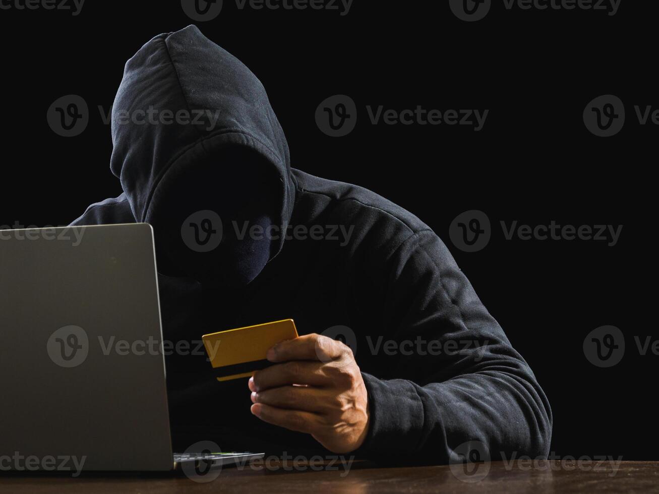 Portrait hacker spy man one person in black hoodie sitting on table looking computer laptop used login password attack security to data digital internet network system night dark background copy space photo