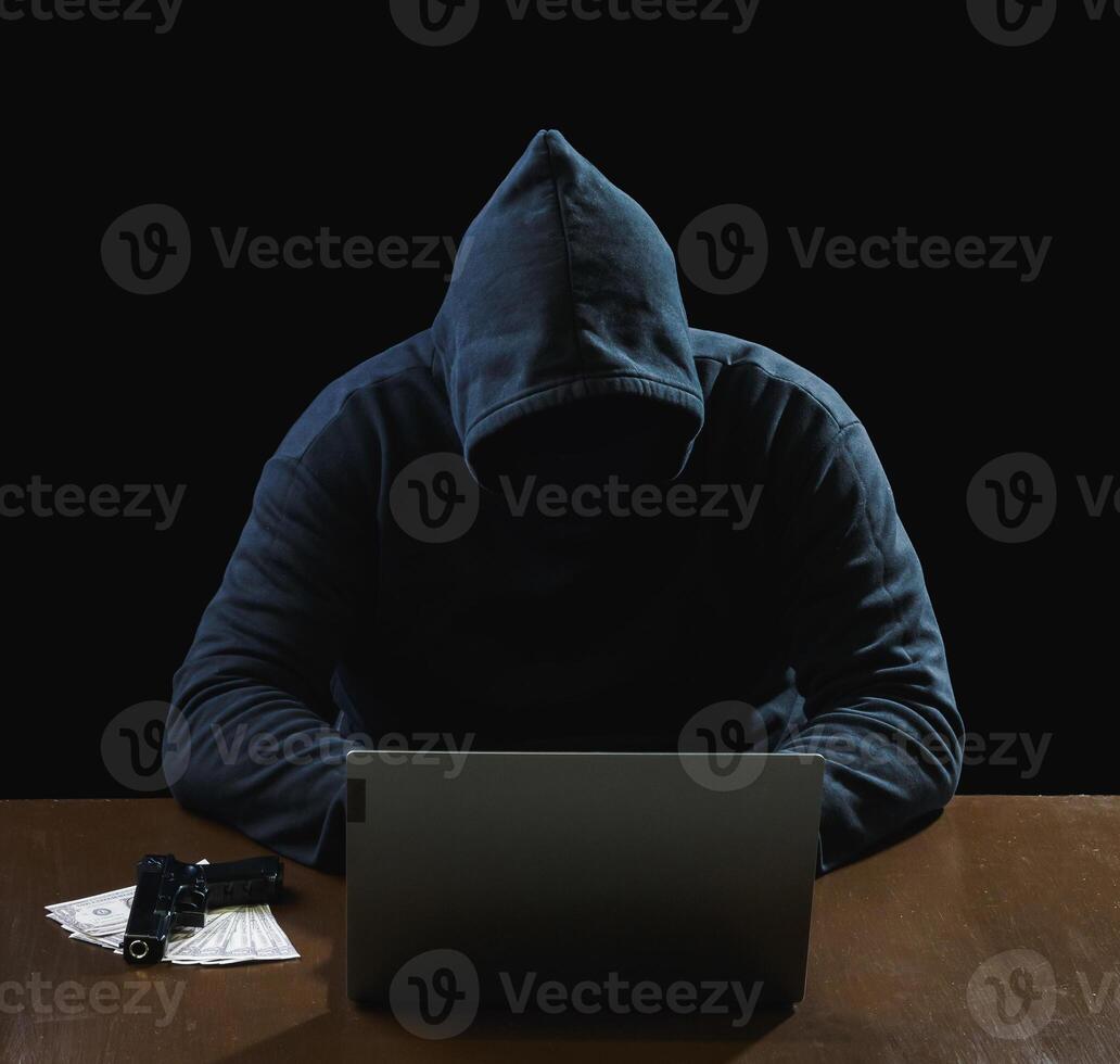 Portrait hacker spy man one person in black hoodie sitting on table looking computer laptop used login password attack security to data digital internet network system night dark background copy space photo