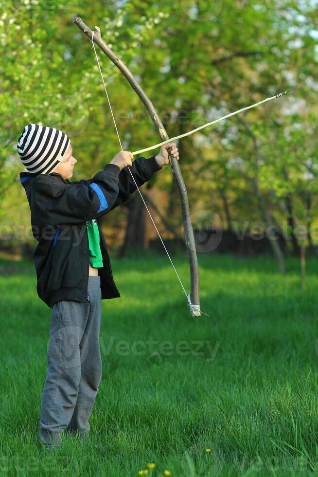 Boy shooting with a hand made bow and arrow. Archery photo