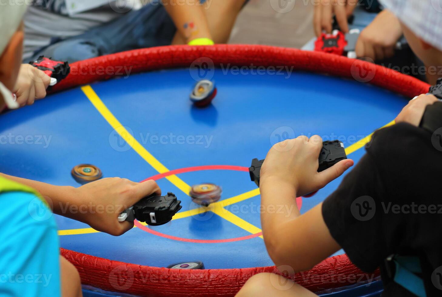 Boys playing popular game beyblade with special spinning tops at the central park. photo