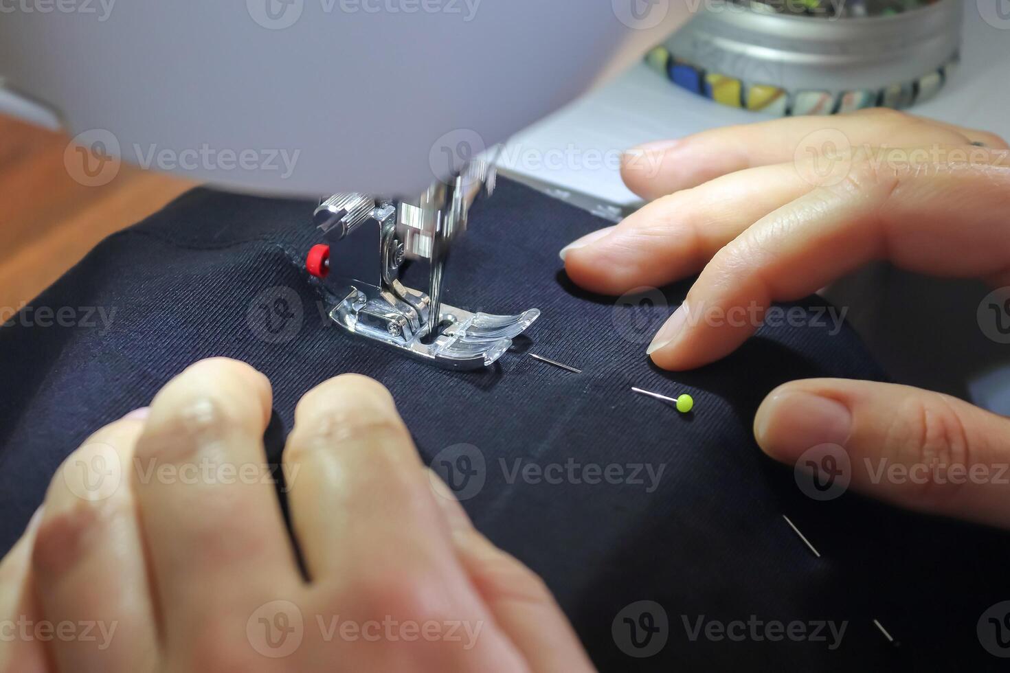 Sewing concept. Female hands working at a modern sewing machine with some fabrics and textiles photo