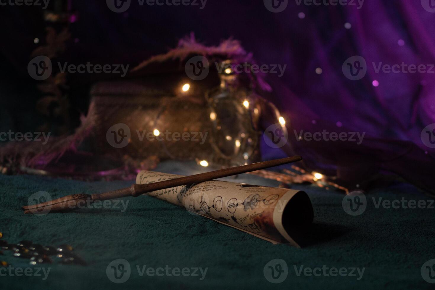 A magic wand carved from wood lies on a scroll with spells on a velvet green cloth among magical paraphernalia on a shining background with lights. Wizard's Things Close-Up photo