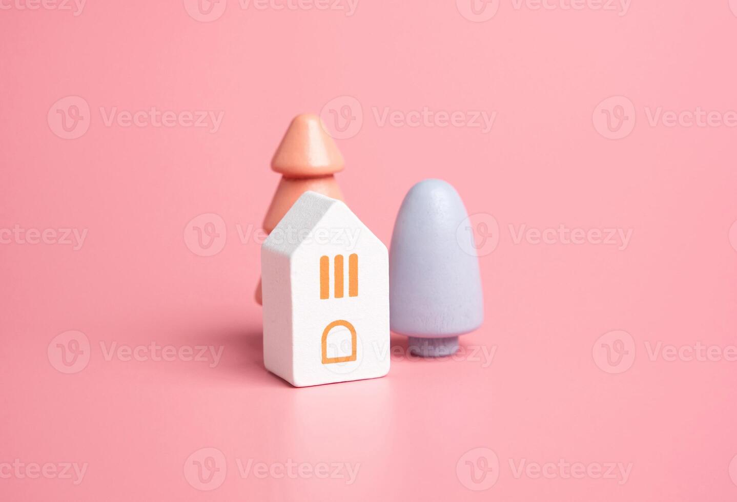 House and colorful trees on a pink background. Wooden figurines toys. Buy a house. Good housing. Mortgage. Cozy and gentle tones. Pastel pink colors. photo