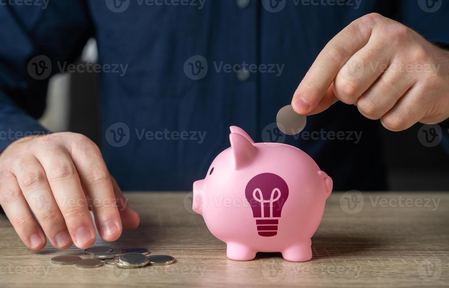 Save up for an idea. A man throws coins into a piggy bank with an idea light bulb symbol. Find investments. Encourage action. Inspire to buy. Invest in the successful launch of a startup. Patenting. photo