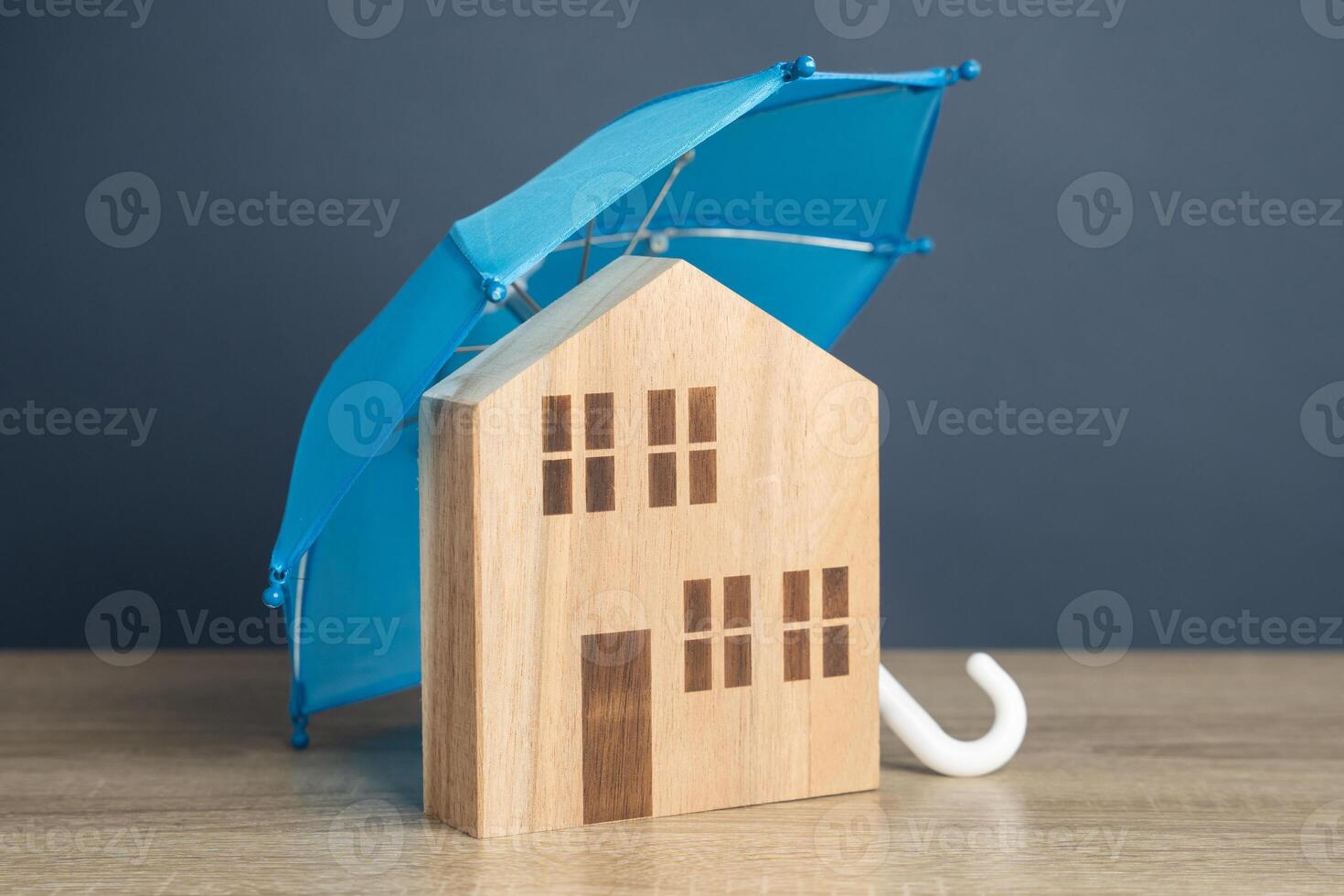 House with blue umbrella. Property insurance. Financial security. Protect investment and be prepared for unforeseen events. Repairs or rebuilding in the event of a covered loss. photo