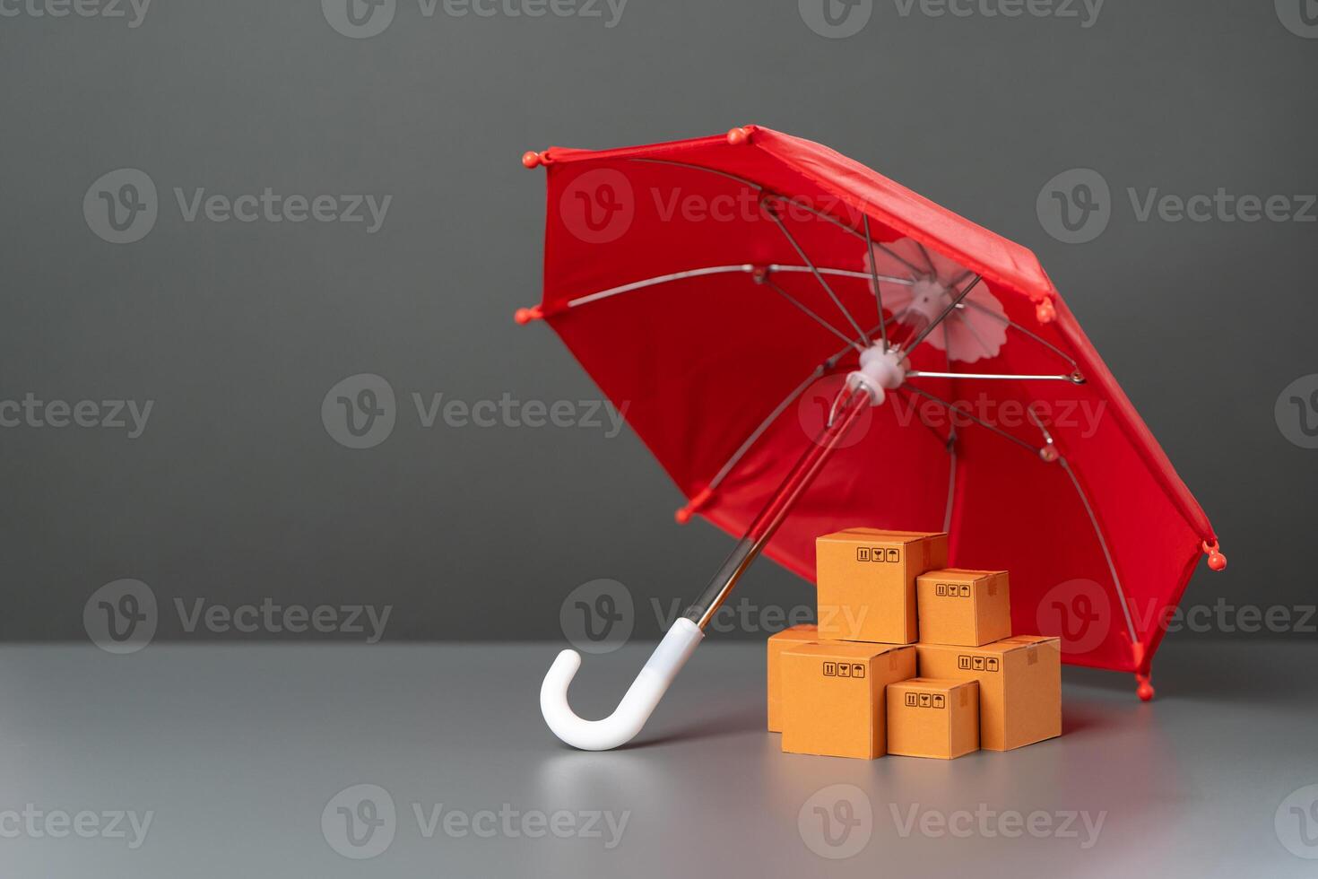 Boxes with goods under a red umbrella. Cargo and parcel insurance. Warranty obligations. Logistics security. Protection of national producer market. Imposing protective duties on foreign competitors. photo