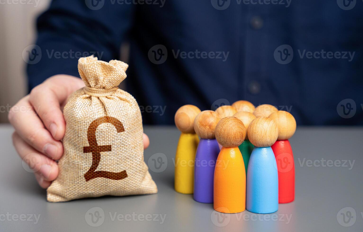 A businessman holds a british pound sterling money bag near a group of people figurines. Preferential loans for entrepreneurs and businesses. Social support. Allocation of budget money for projects. photo