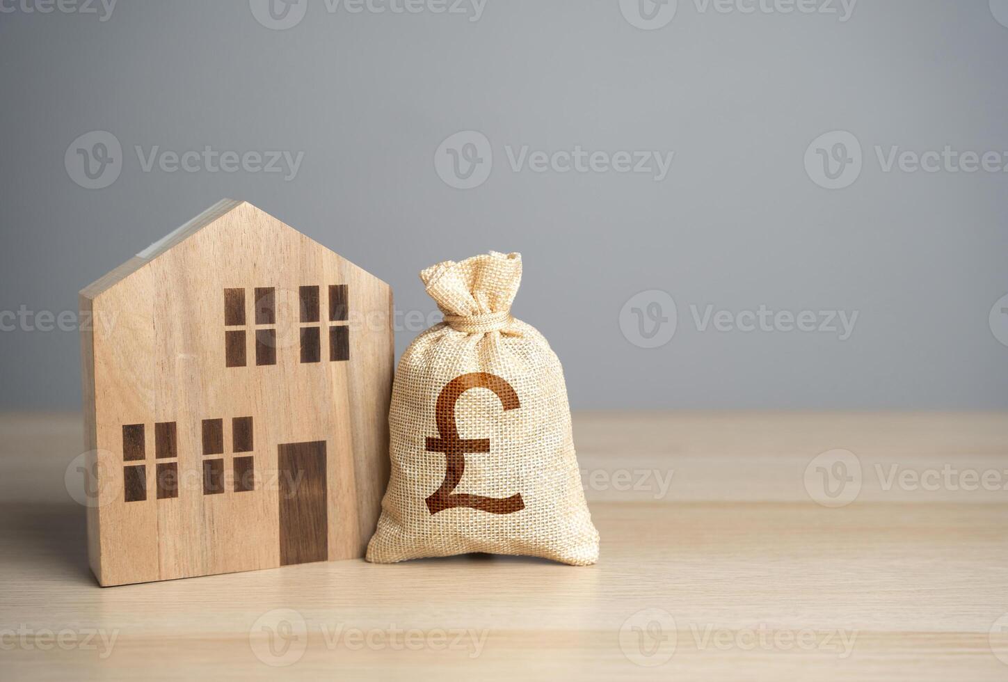 Wooden house figure and british pound sterling money bag. Taxes. Property value appraisal. Make a deal. Housing prices. Buying and selling real estate. Property Insurance. photo