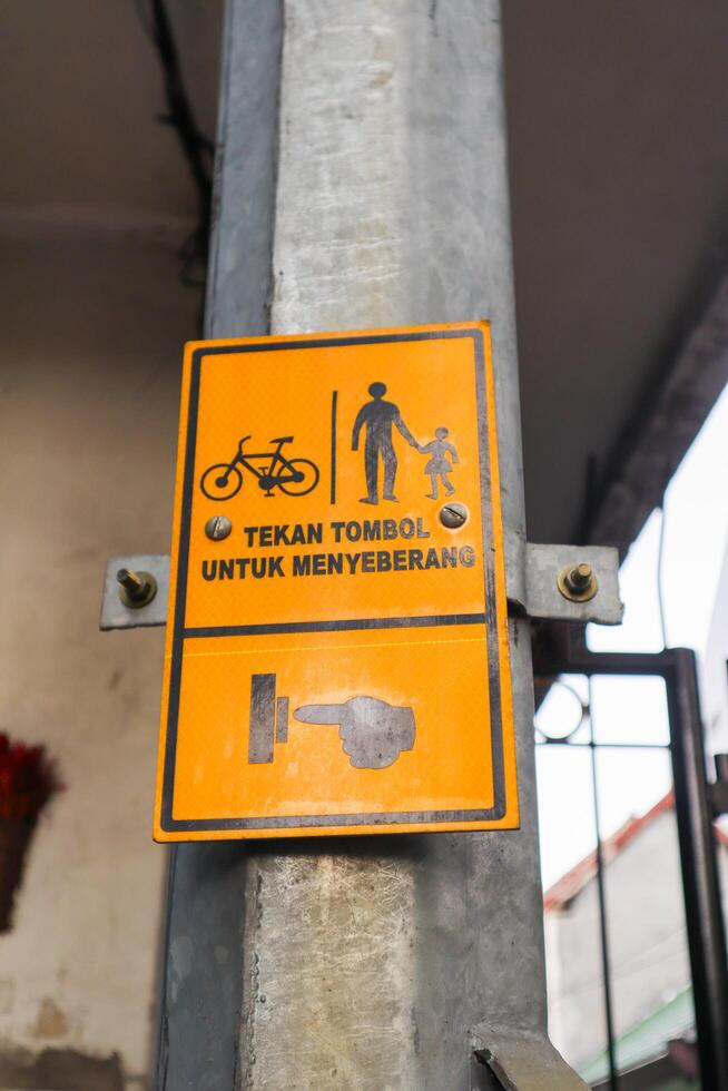 a sign with text press a button if pedestrians want to cross. surabaya, indonesia - 6 maret 2024 photo