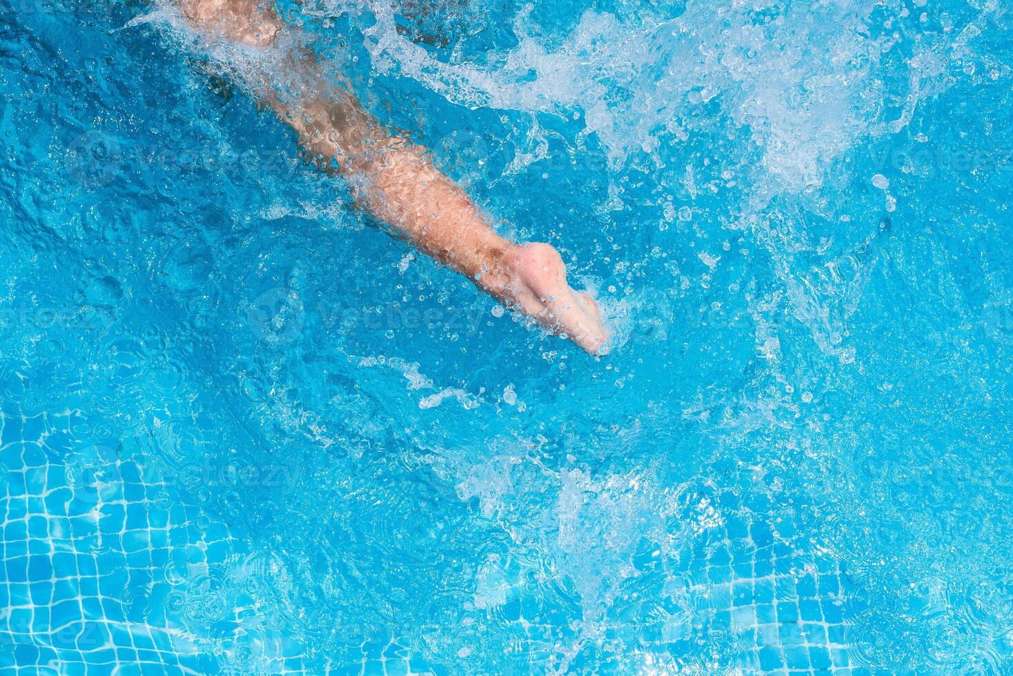 Child splashing in the cool water of a pool in summer photo