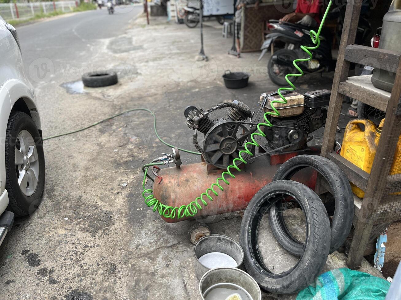 Car repair shop, air pump machine compressor, pile of used oil bottles and used tires photo