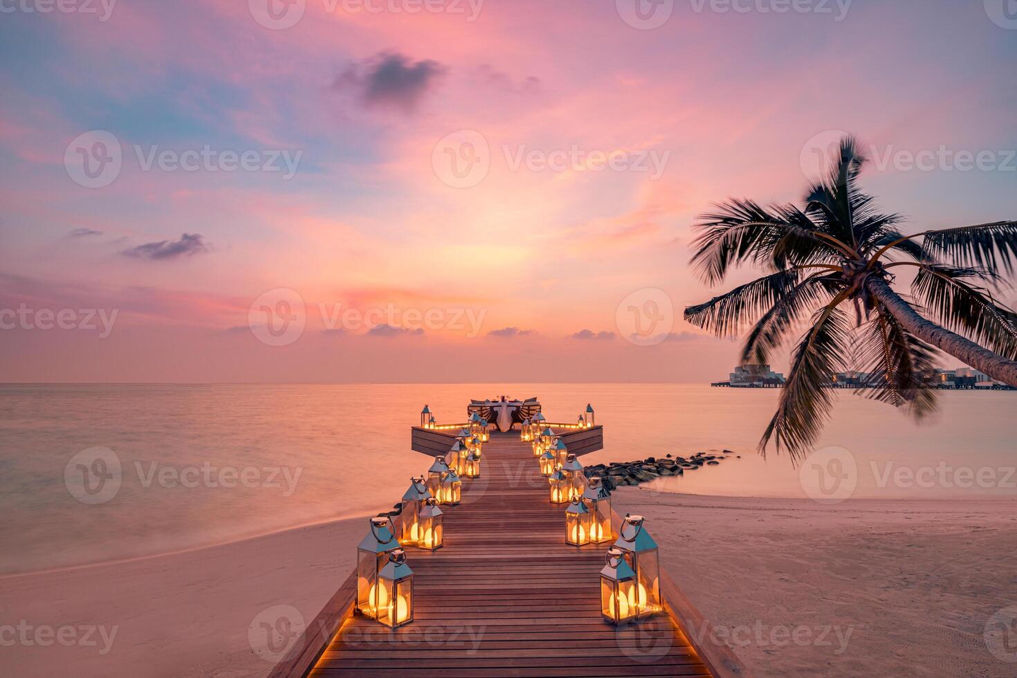 cena romántica en la playa con puesta de sol, velas con hojas de palma y cielo y mar al atardecer. vista increíble, paisaje de luna de miel o cena de aniversario. isla exótica horizonte nocturno, romance para una pareja foto