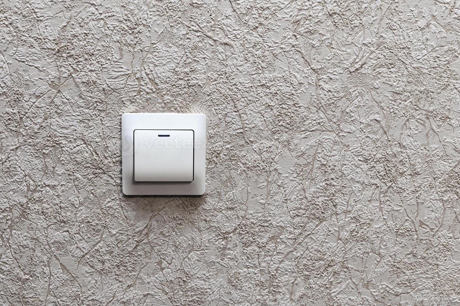 white light switch on beige wall with wallpaper photo