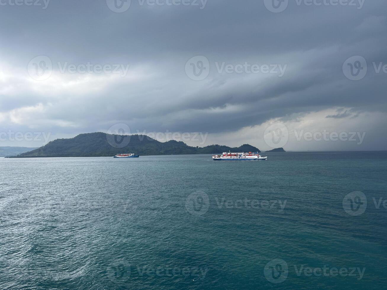 Sea landscape with dark sky above the ship with a mountain background photo