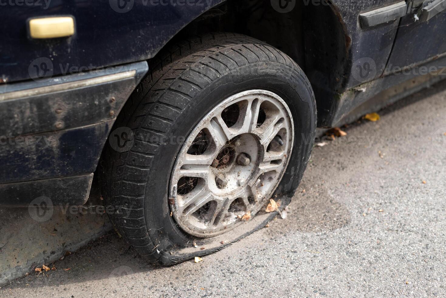 Close-up damaged tire. The wheel of car tire leak. Flat tire waiting for repair. Abandoned car in the parking lot. photo