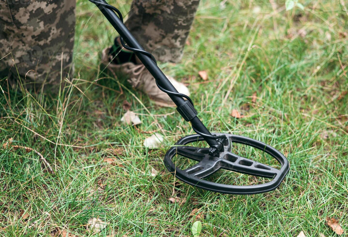 Soldier using a metal detector in fields. Ukrainian Explosive Ordnance Disposal Officer detecting metal by metal detector device photo