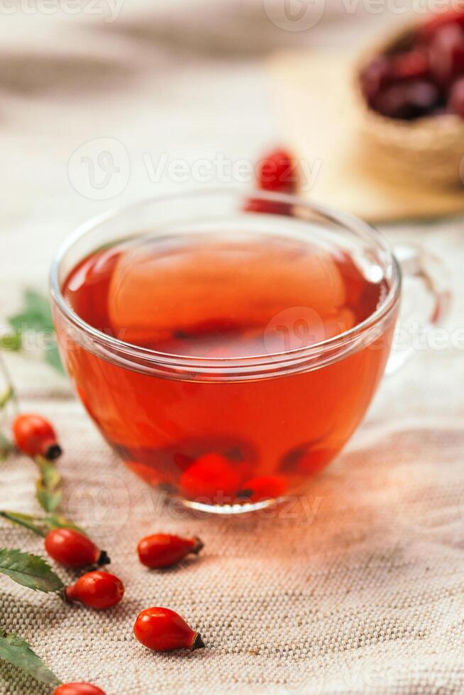 A cup of rose hip tea with fresh berries in a glass cup. Vintage background, selective focus photo