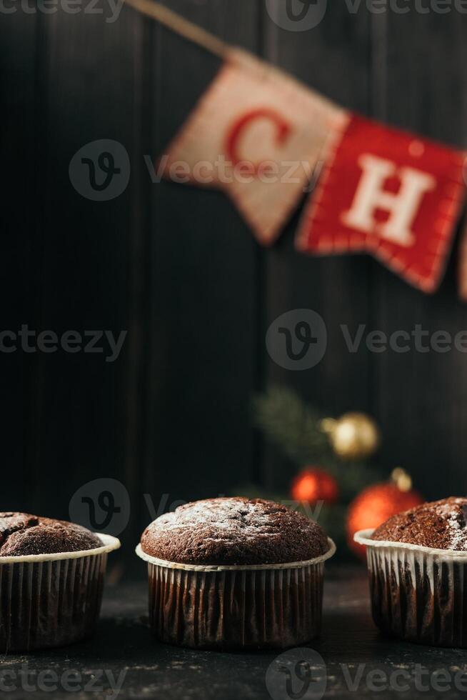chocolate muffins with powdered sugar on top on a black background. Christmas decoration . Still life close up. Food photo