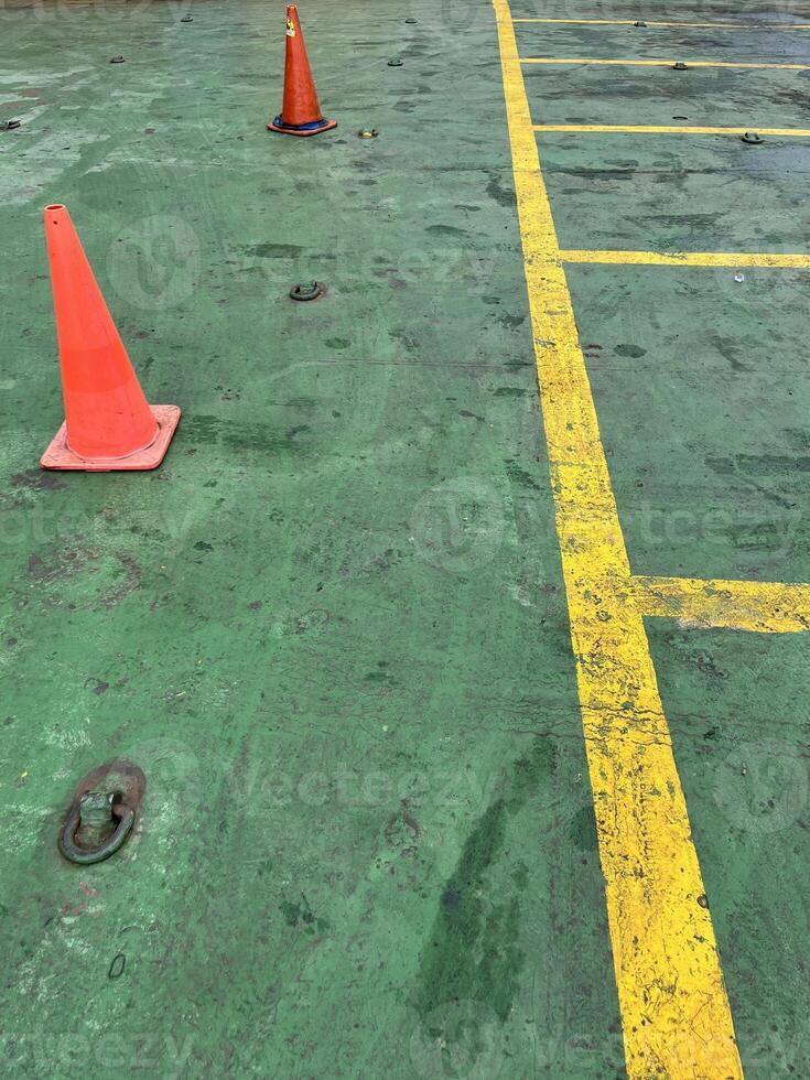 Road symbol cone in rest area parking lot and ship with yellow guide lines for cars photo