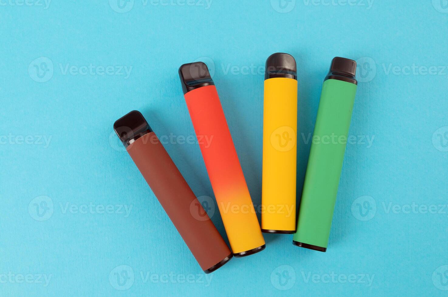 Set of colorful disposable electronic cigarettes on a blue background. The concept of modern smoking. Top view photo