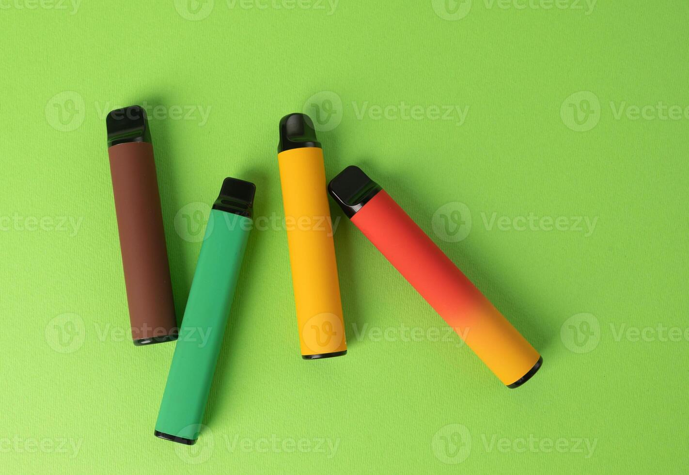 conjunto de vistoso desechable electrónico cigarrillos en un verde antecedentes. el concepto de moderno de fumar. parte superior ver foto