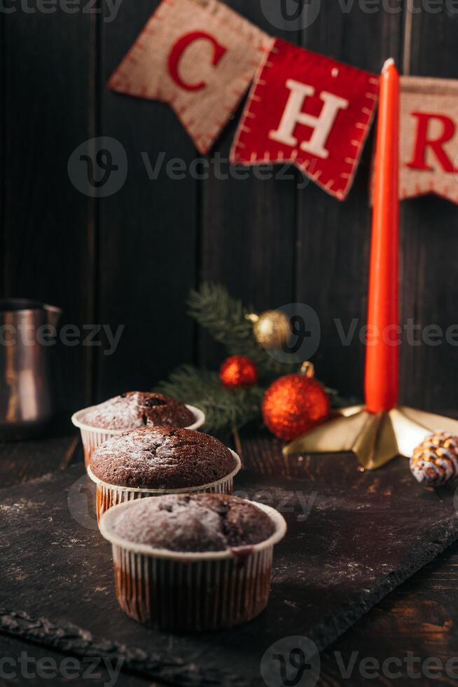 chocolate muffins with powdered sugar on top on a black background. Christmas decoration . Still life close up. Food photo